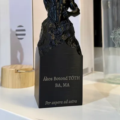 Schwarze Trophäe auf eckigem Sockel mit hell graviertem Namen, Titel und Wahlspruch