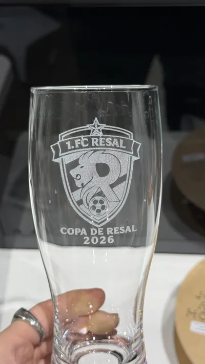 Weizenbierglas mit graviertem Fußball-Vereinswappen und Turniernamen, in der Hand