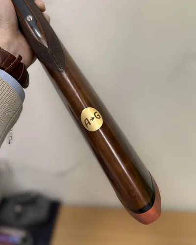 Gewehrschaft aus Holz mit eingelassener runder Messingplakette mit Initialen