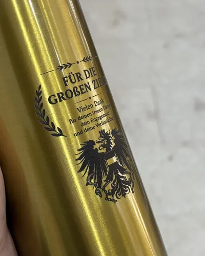 Goldfarbene Trinkflasche mit graviertem Dankestext, Lorbeerzweig und Wappenmotiv