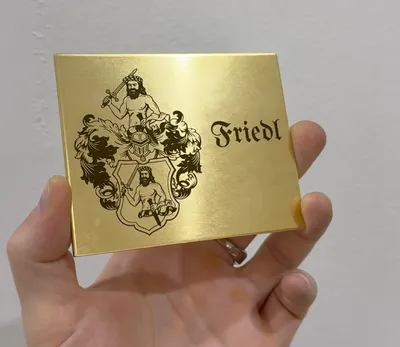 Goldfarbenes Messingschild mit graviertem Familienwappen und Namen in Frakturschrift